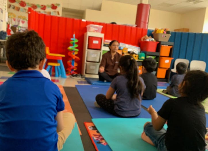 Adult and children sitting on mats in a classroom