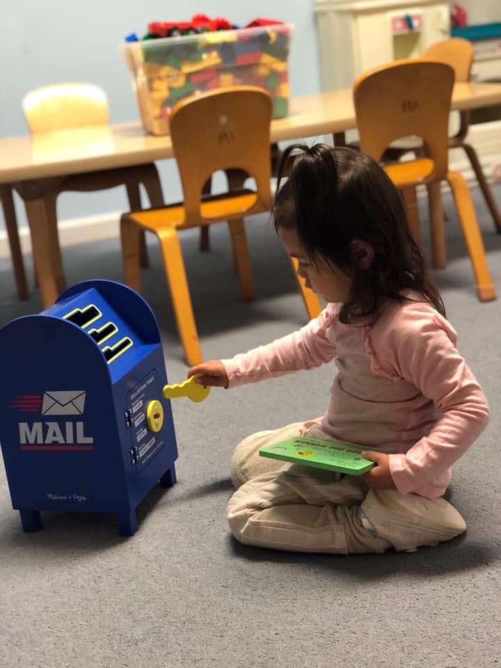 Child playing with a toy mailbox in a classroom