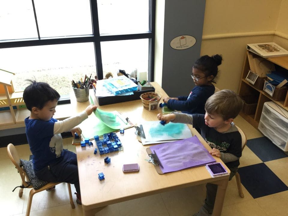 Three children sitting at a table doing an art activity