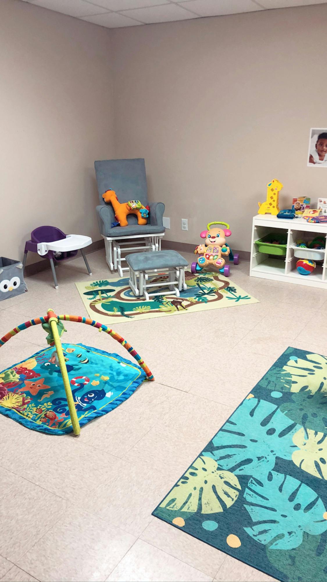 Playroom with a rocking chair, play mat, and toy shelf