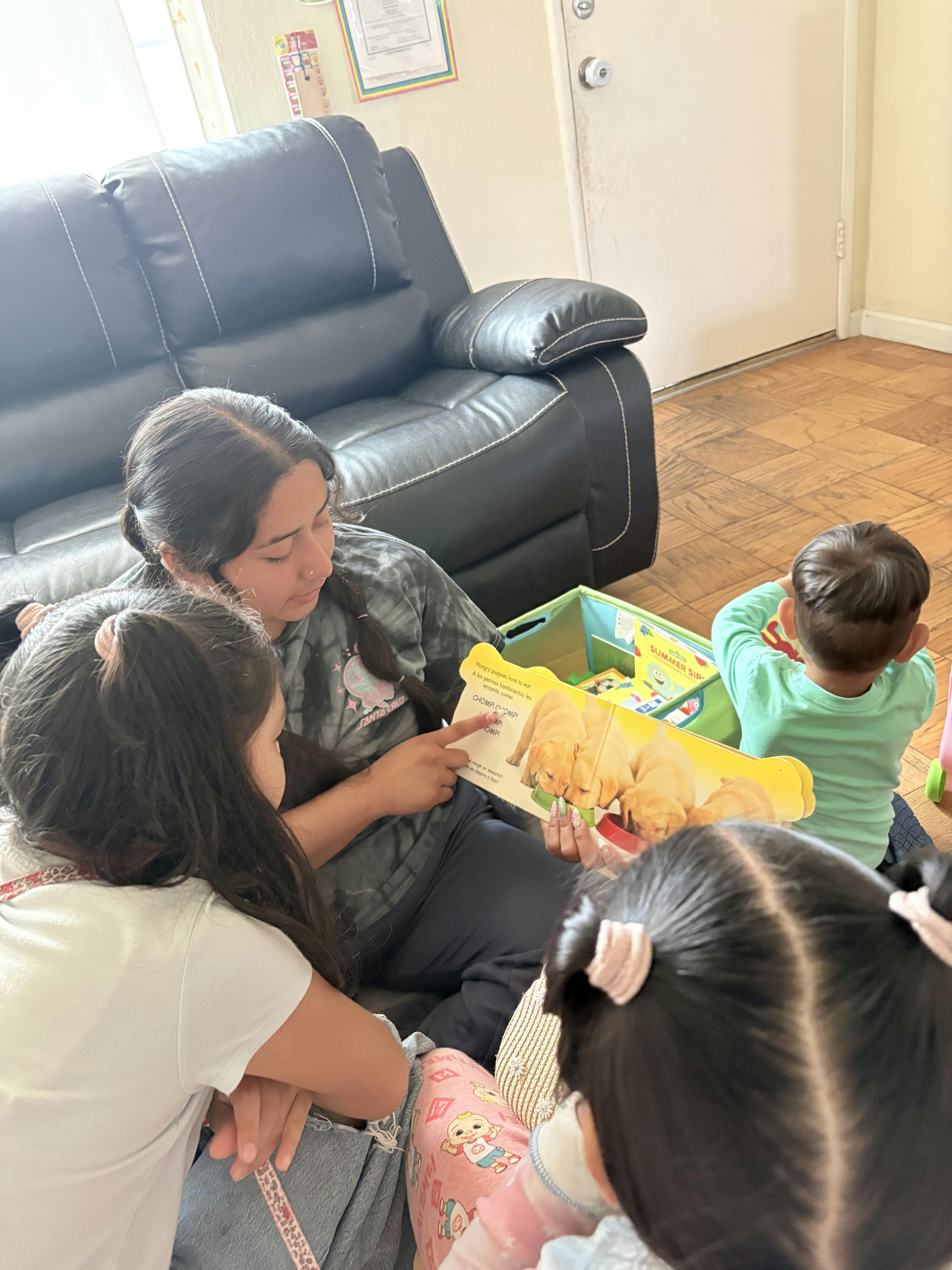 A person reading a book about puppies to three children