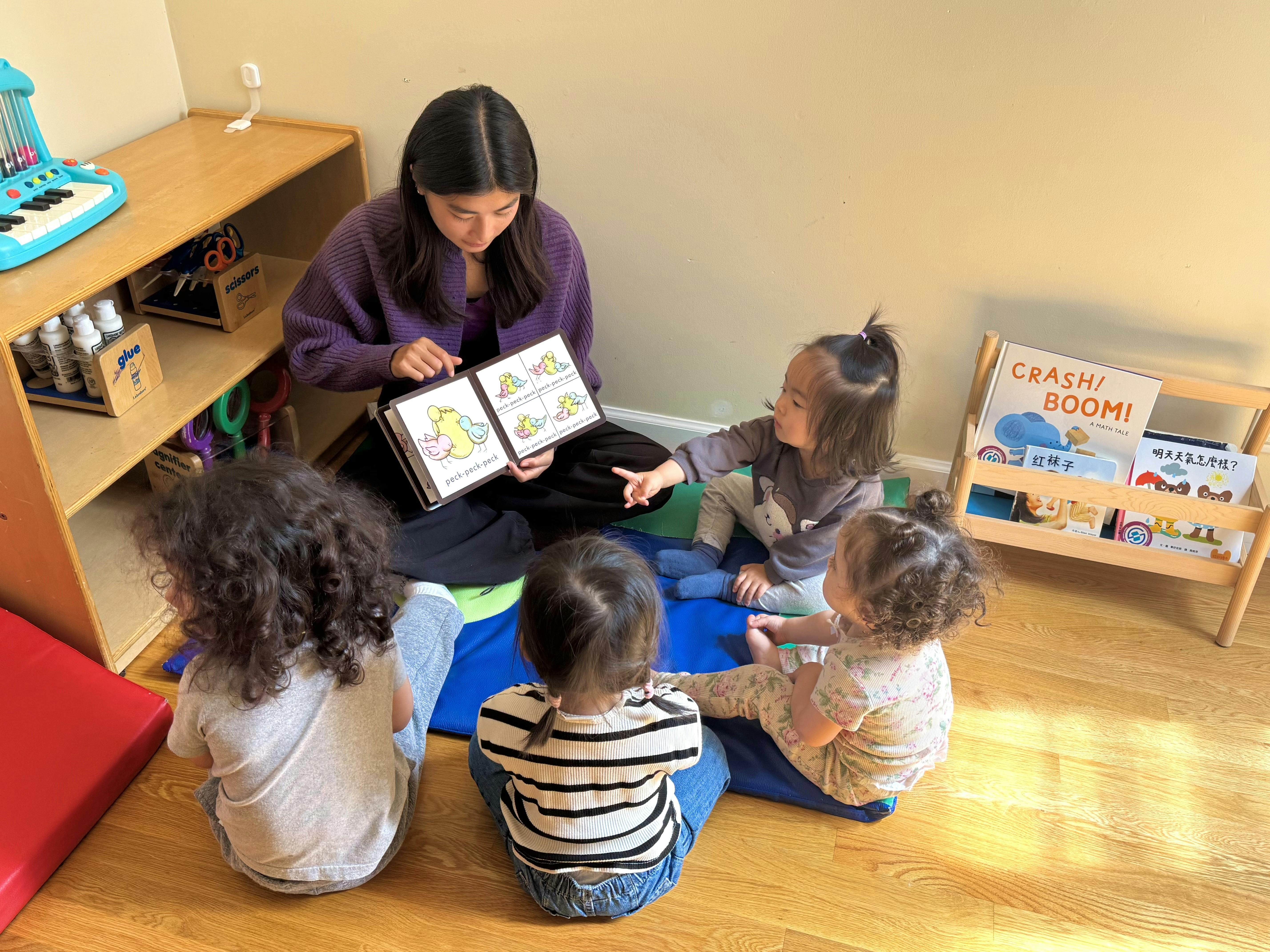 Adult reading a book to a group of children in a classroom