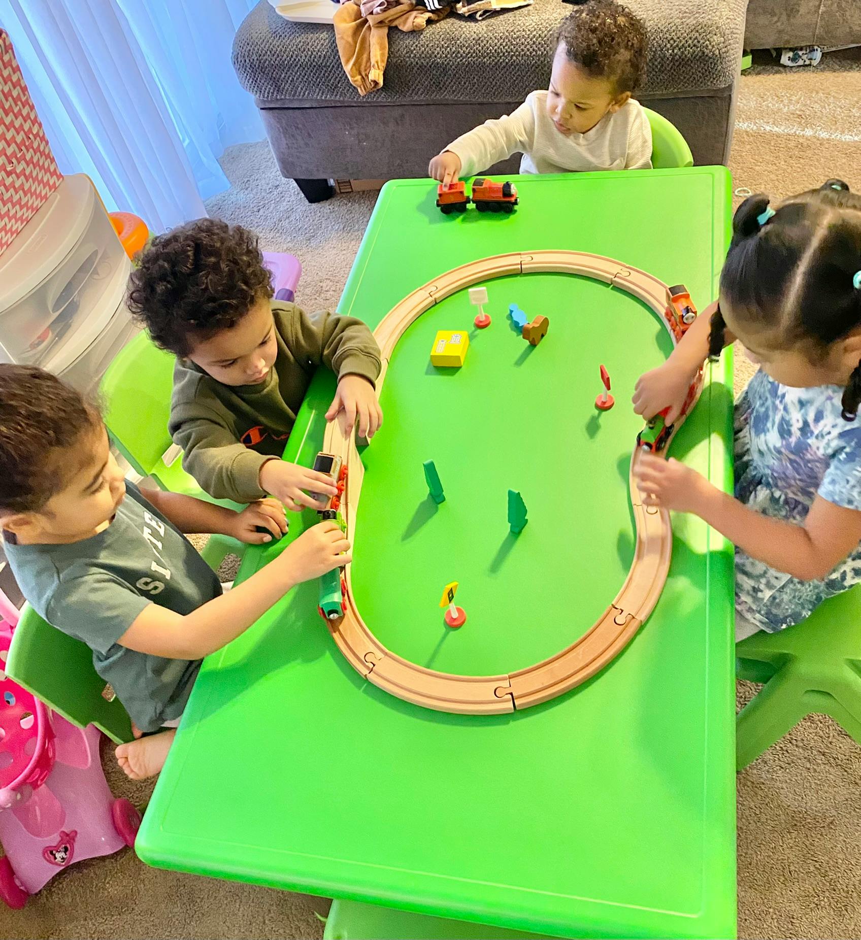 Children playing with a toy train set on a green table