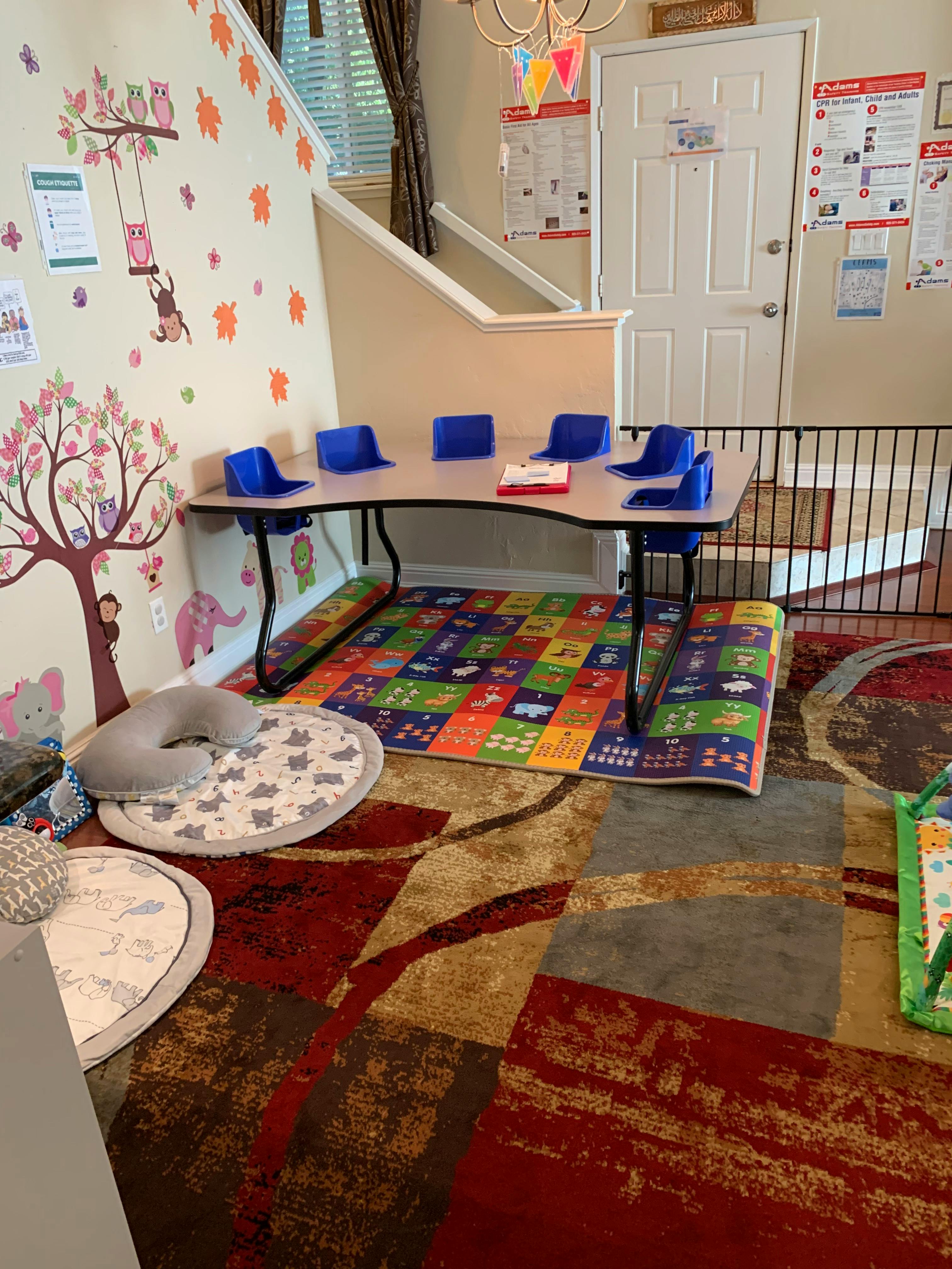 Children's play area with a small table and blue chairs on a colorful rug