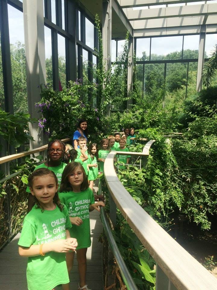 Group of children and adults on a walkway in a greenhouse