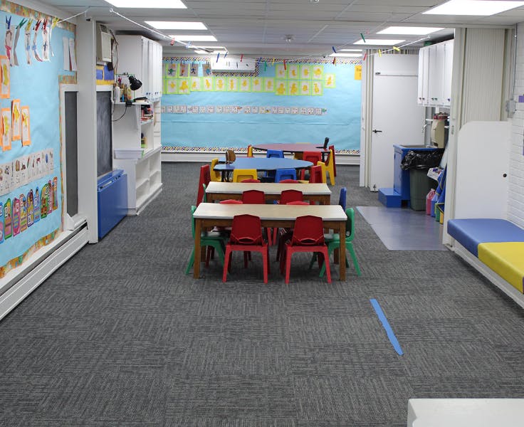 Classroom with small tables and chairs, and colorful decorations on the walls