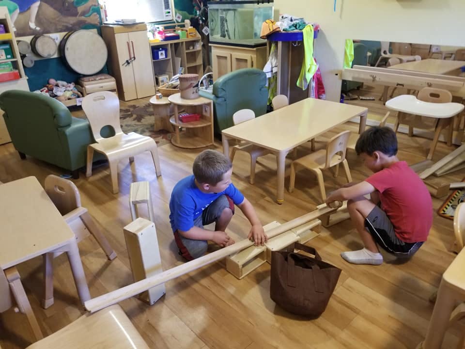 Two children playing with wooden blocks and planks on the floor