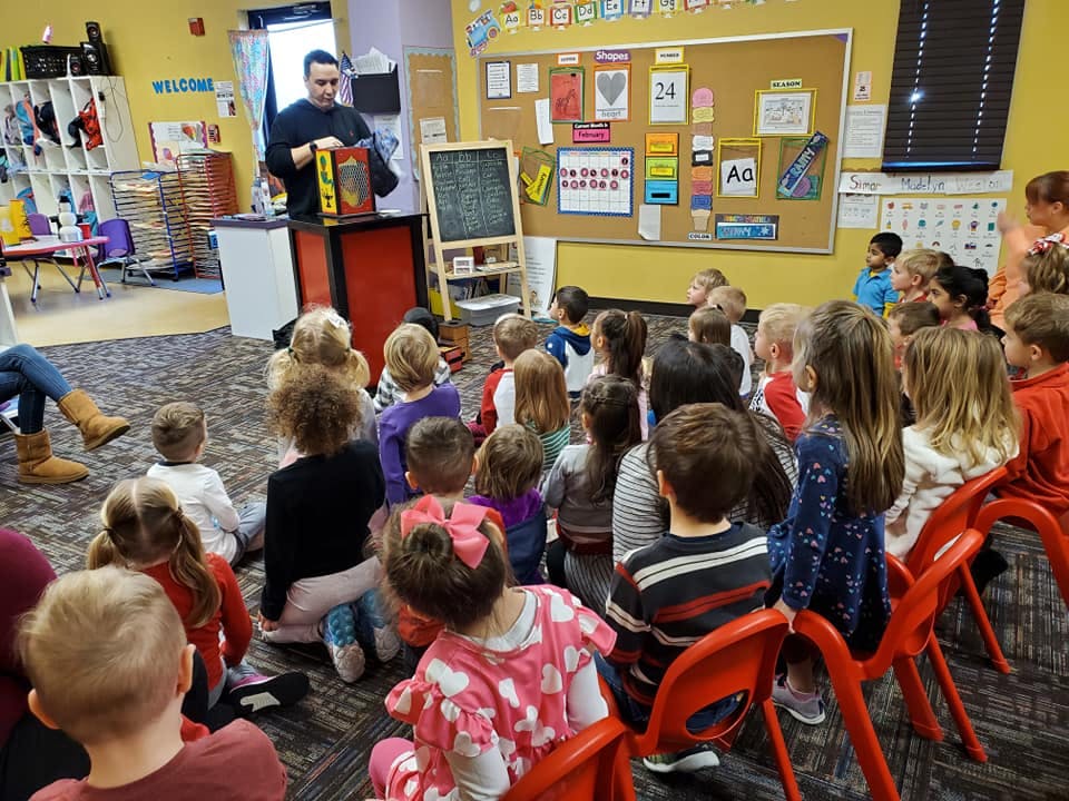 Person performing for a group of children in a classroom