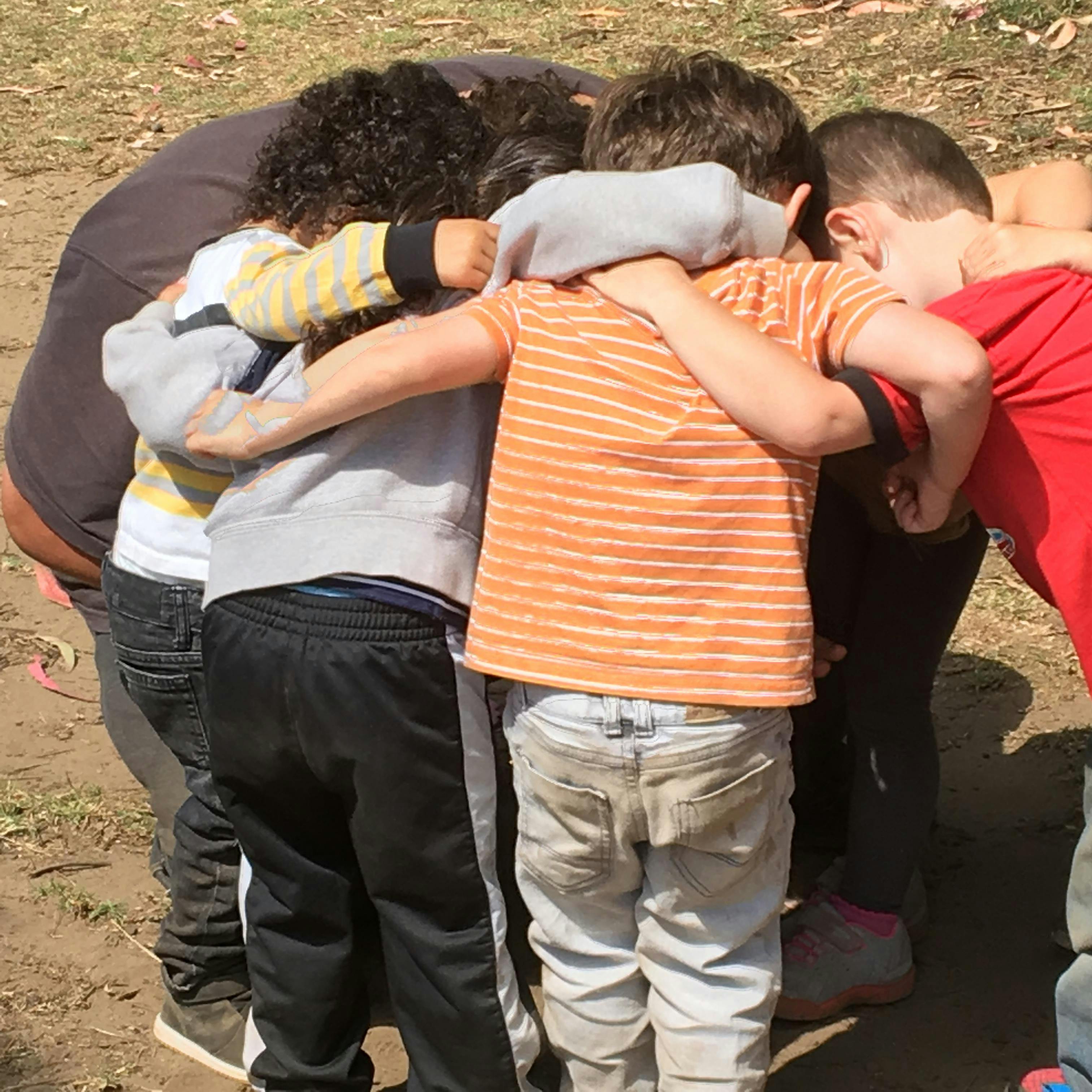 Group of children in a huddle with arms around each other