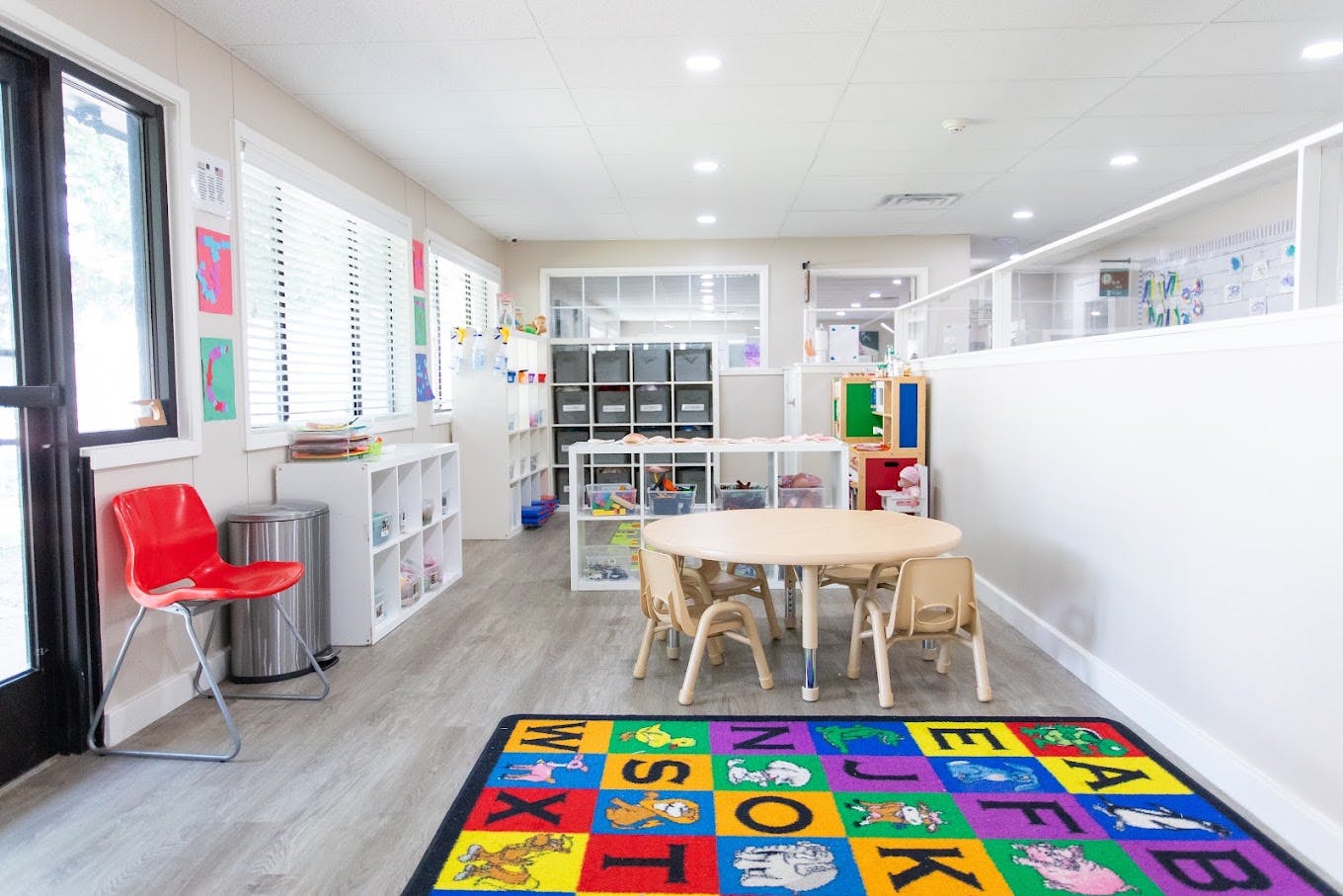 Colorful alphabet rug in a clean, bright classroom with small tables and chairs