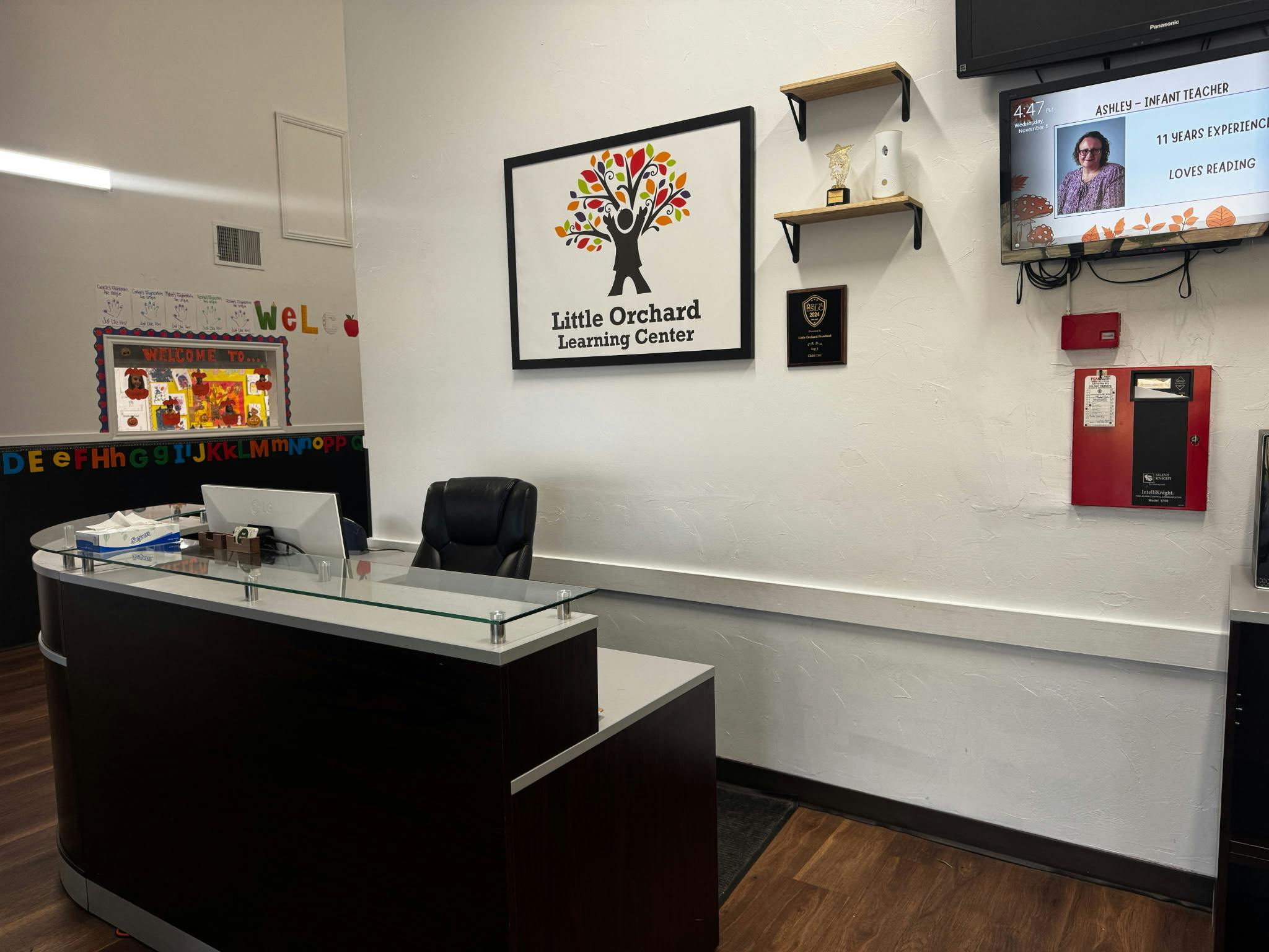 Reception desk with a laptop and a sign for Little Orchard Learning Center