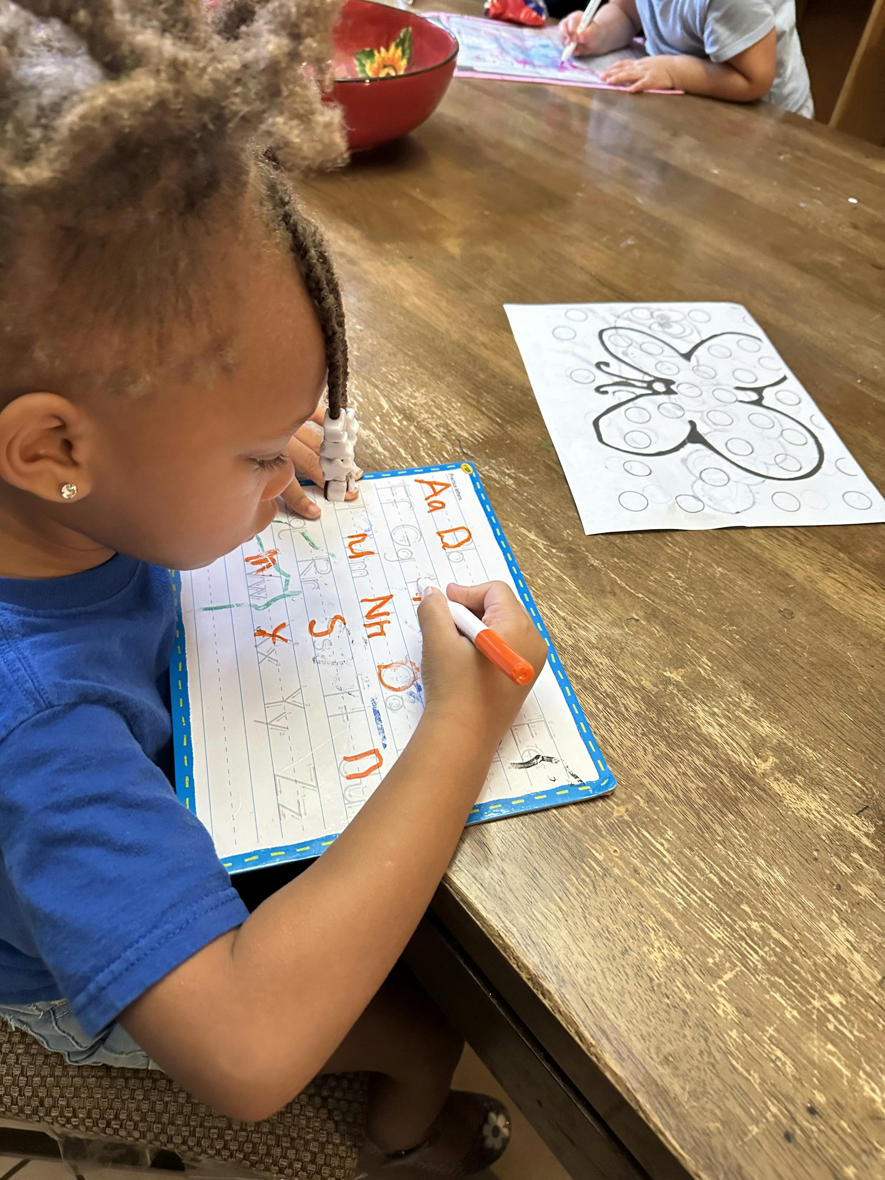 Child writing letters on a whiteboard with a marker