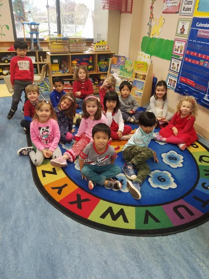 Group of children sitting on an alphabet rug in a classroom