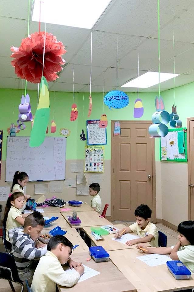 Children sitting at desks in a classroom, some writing