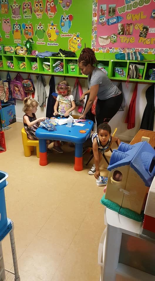 Adult supervising children at a small table in a classroom