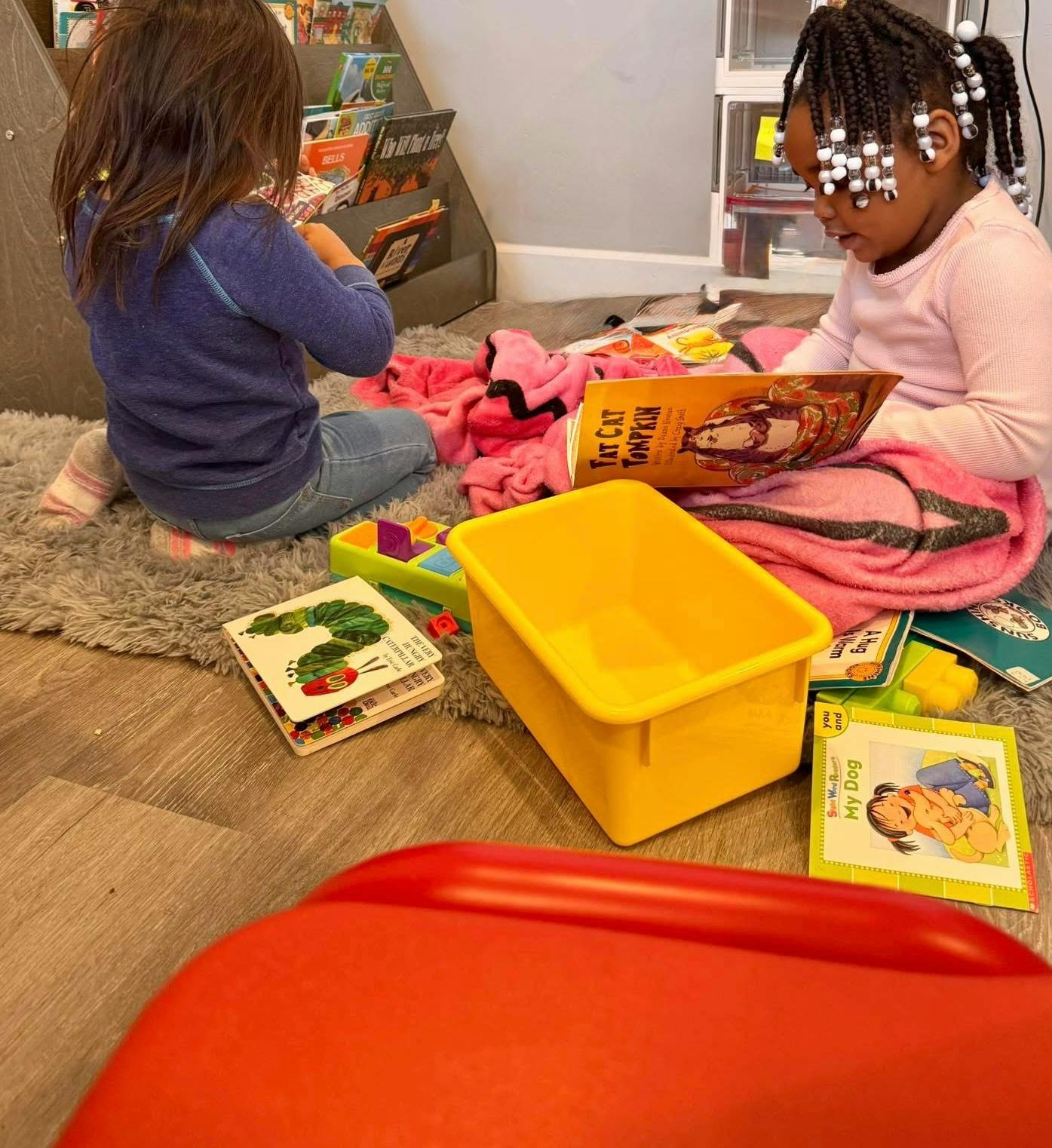 Two children sitting on the floor reading books