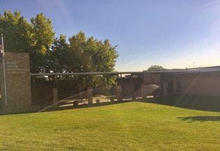 Building exterior with brick walls, covered walkway, and green lawn