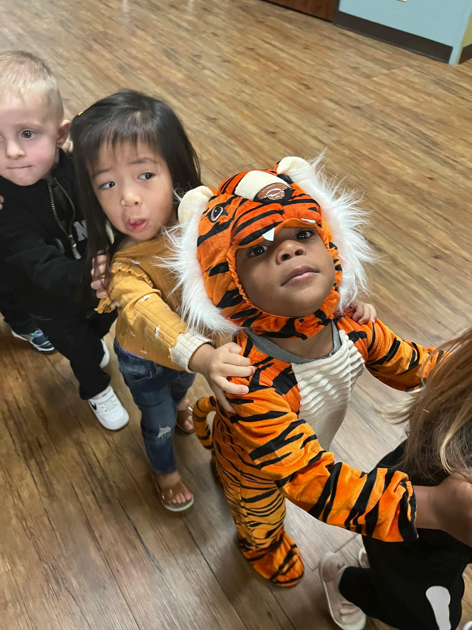 Three children in a line, one in a tiger costume