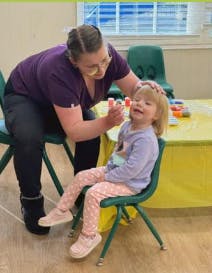 Adult applying face paint to a child