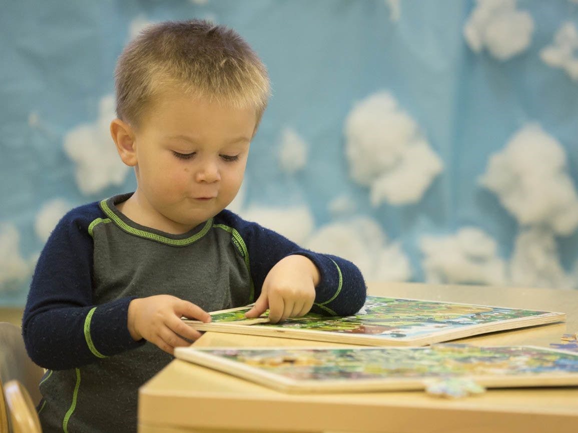 Child playing with a puzzle at a table