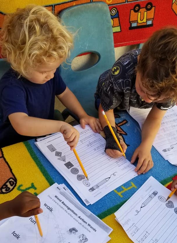 Children writing on worksheets with pencils in a classroom
