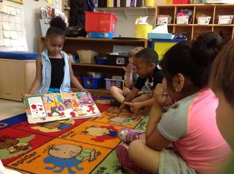 Children sitting on a rug looking at a book
