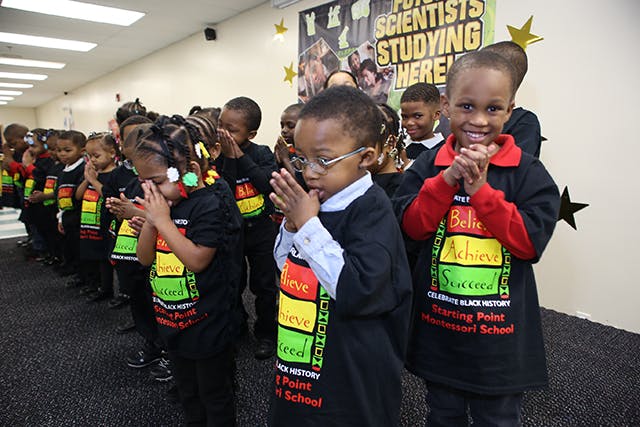 Children standing in a line with hands clasped, some wearing glasses
