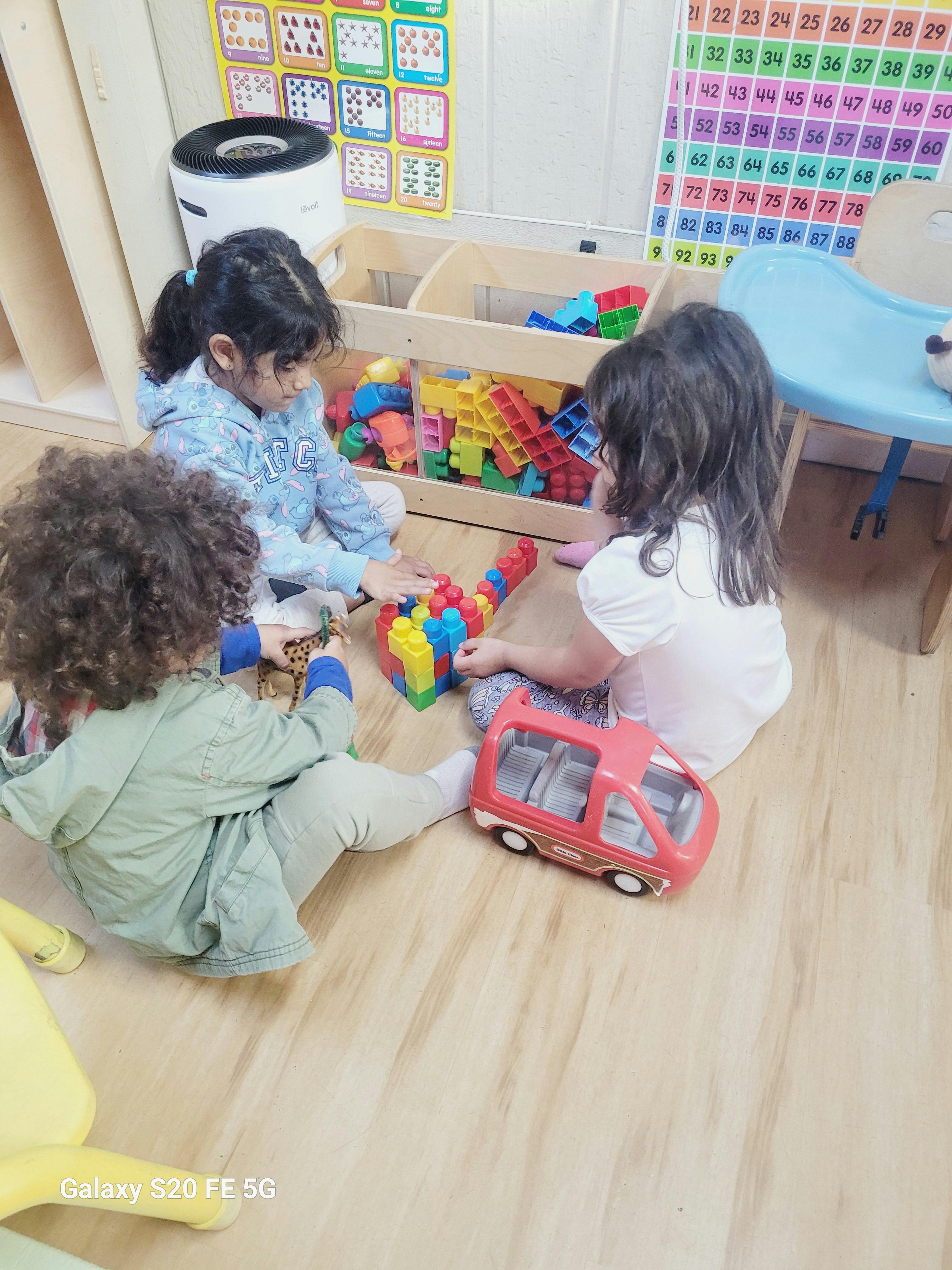 Three children playing with toys on the floor