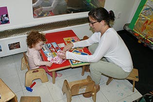 Adult and child at a small table playing with toys