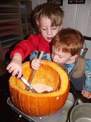 Two children carving a pumpkin