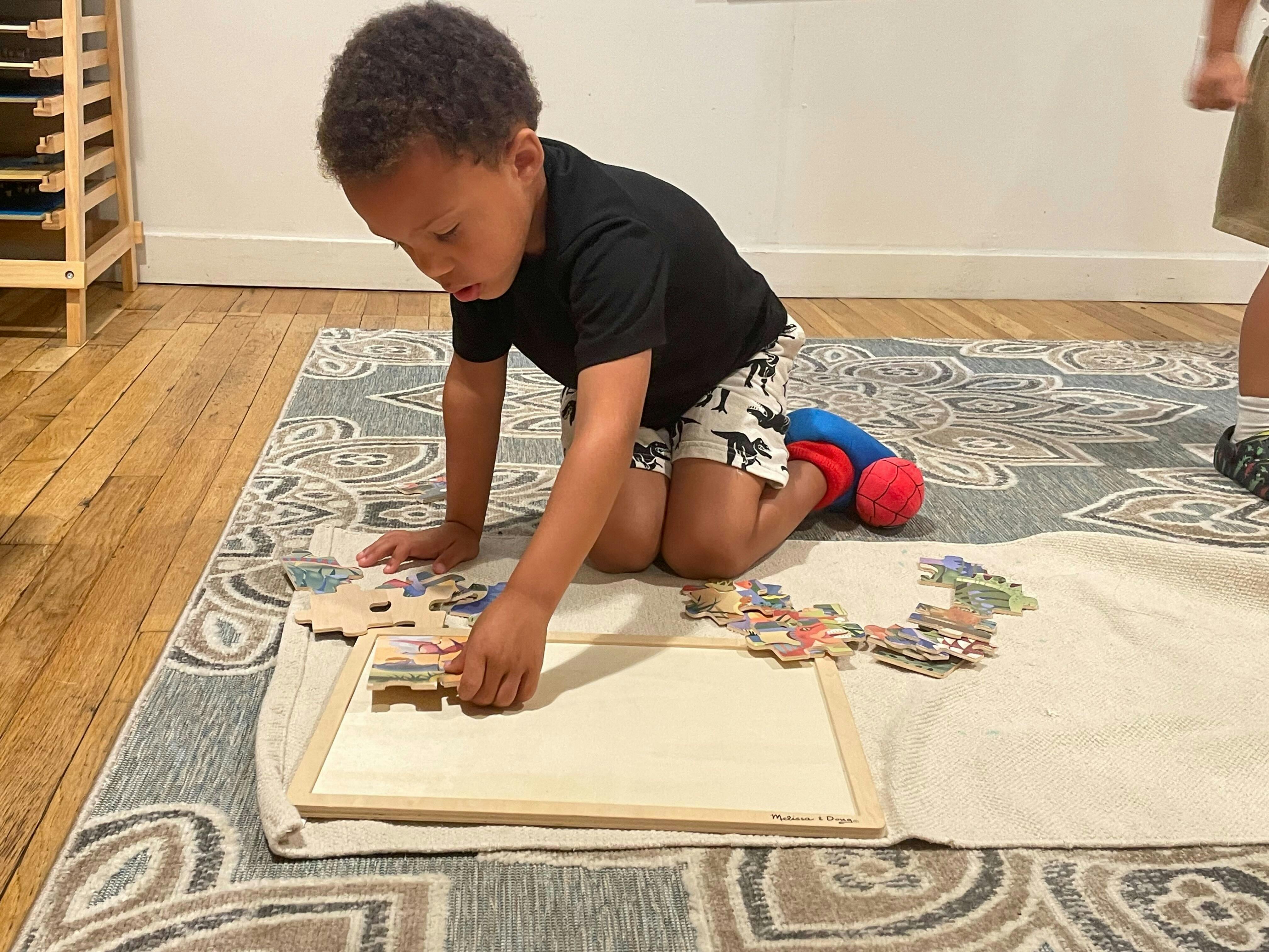 Child kneeling on rug, assembling a puzzle