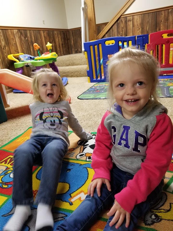 Two children sitting on a colorful rug
