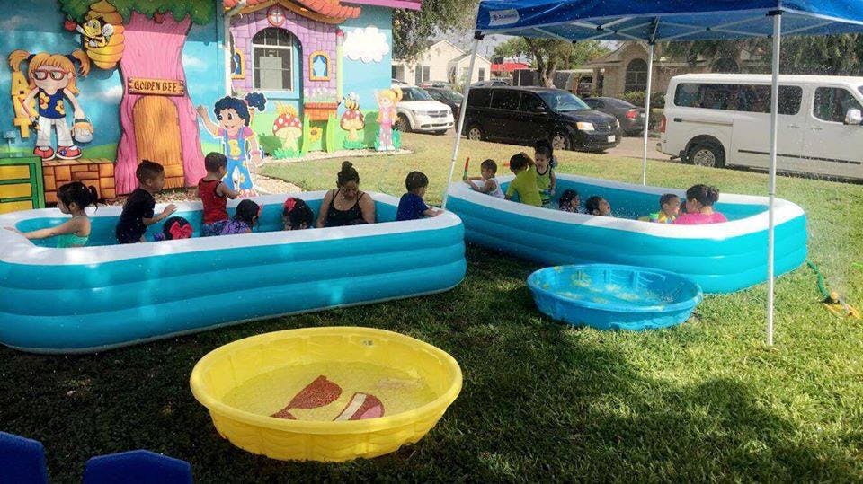 Children and adults in inflatable pools on grass