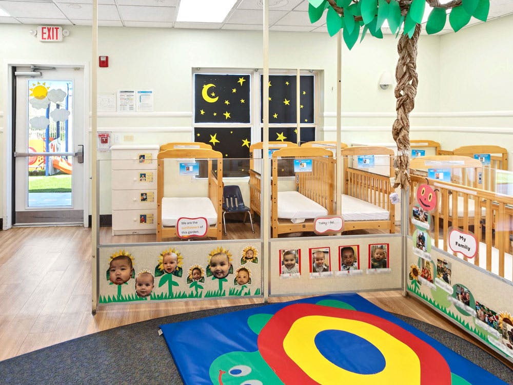 Cribs in a daycare room with an exit door leading to a playground