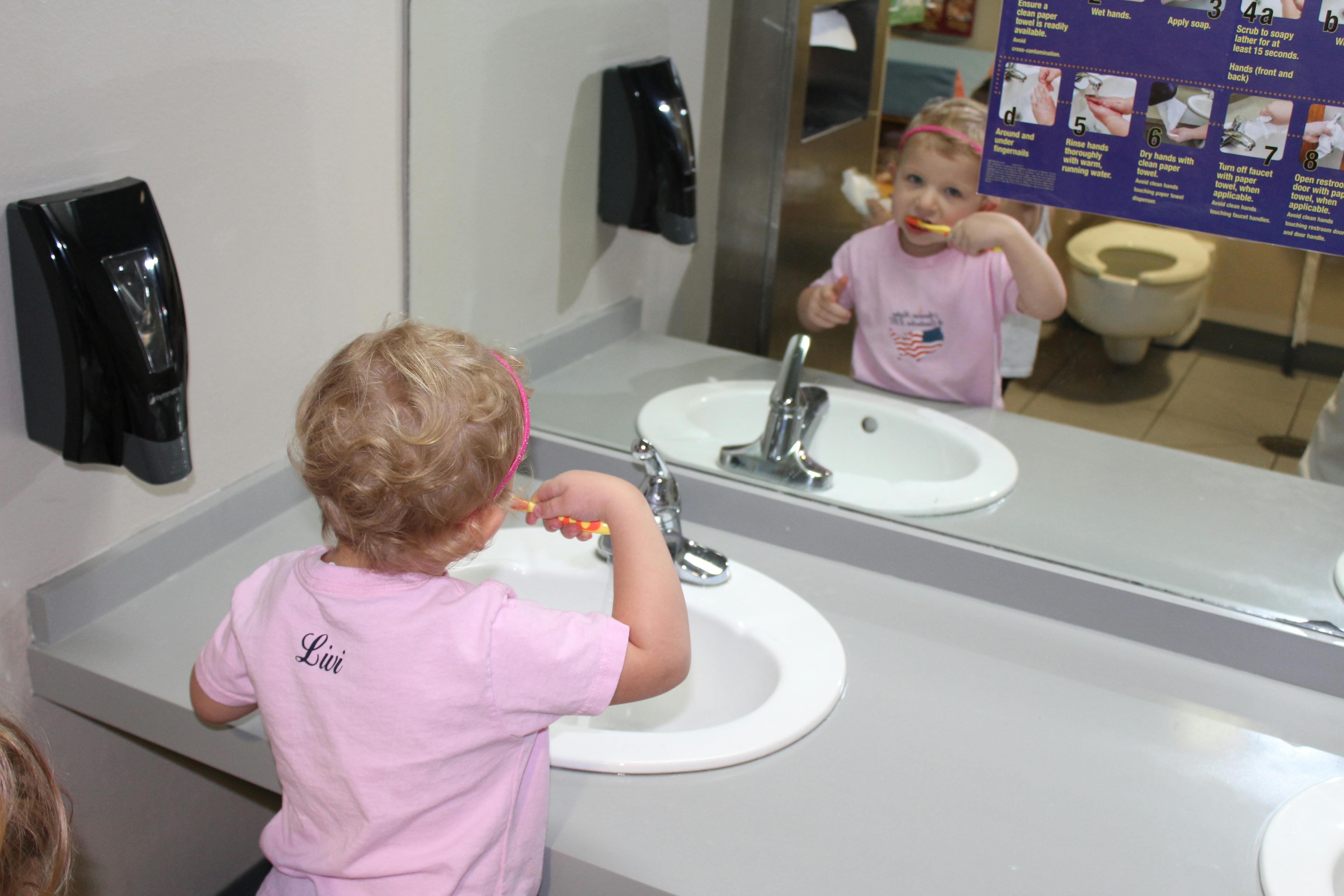 Child brushing teeth in front of a mirror