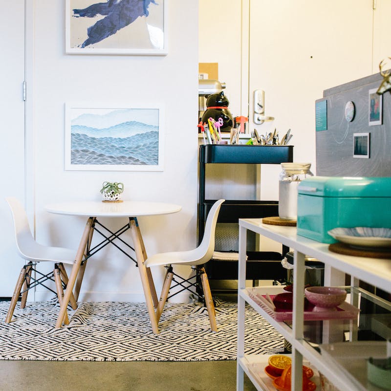 Small round table with two chairs on a patterned rug, next to shelves