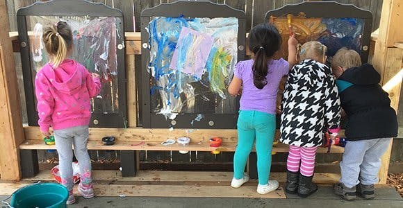 Children painting on easels outdoors