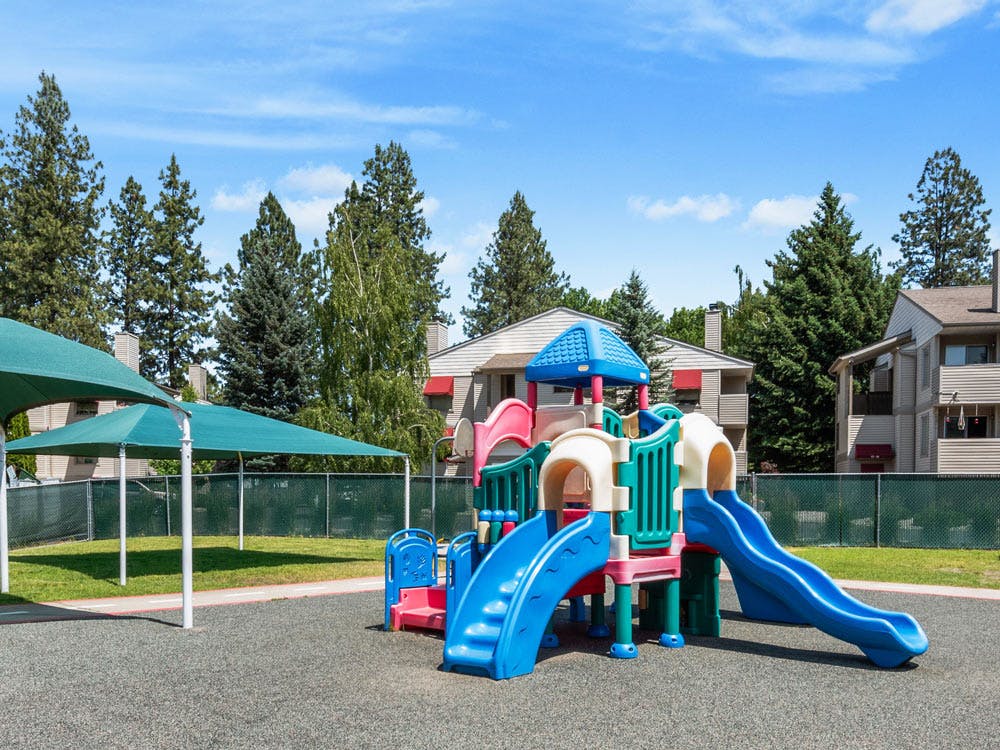 Colorful playground with multiple slides next to green shade structures