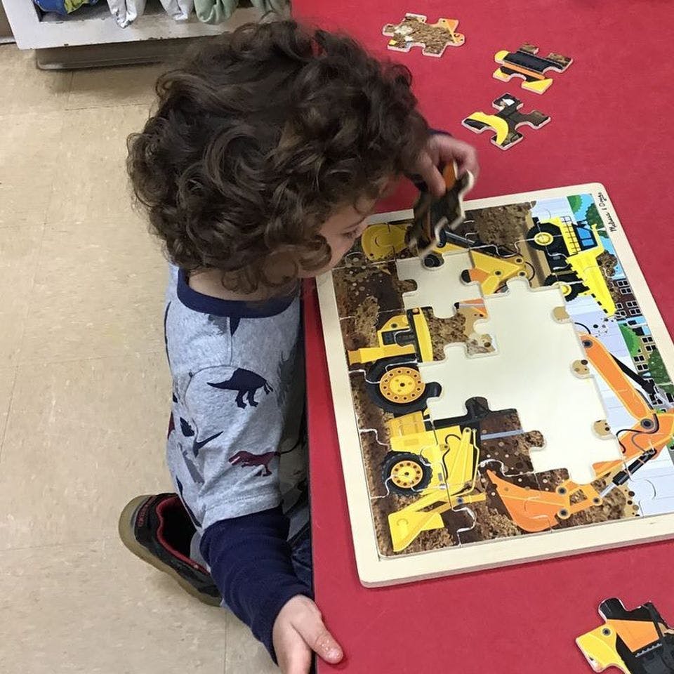 Child playing with a construction vehicle puzzle