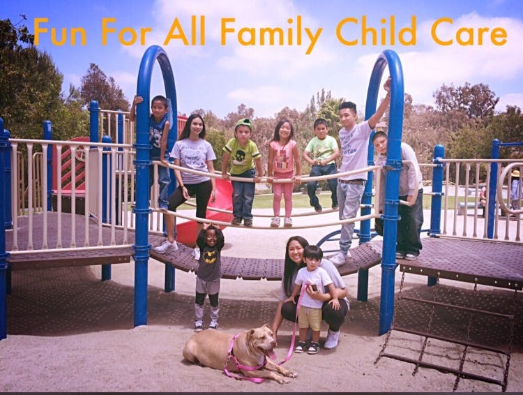 People and children on a playground with a dog