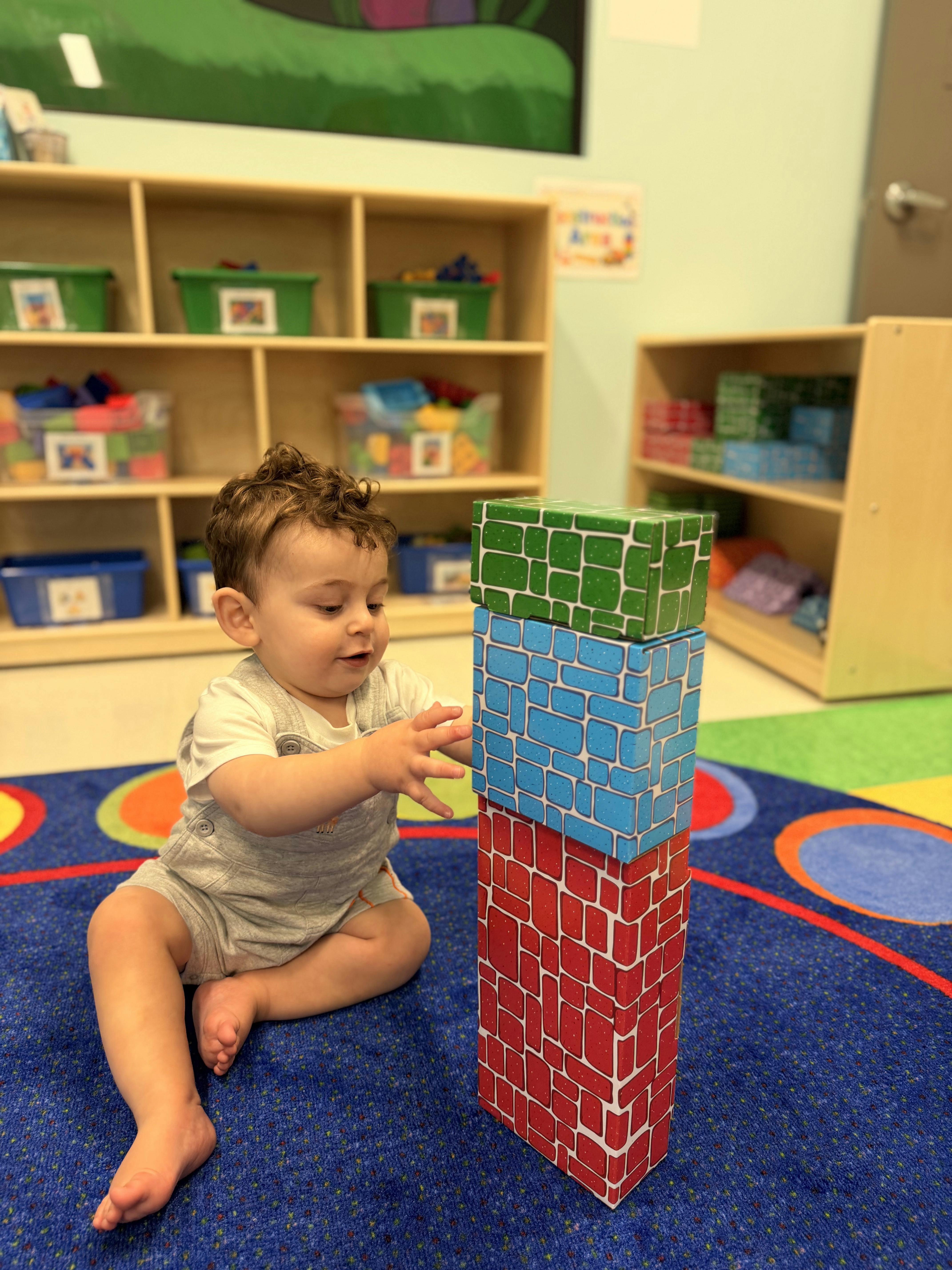 Child building a tower of blocks on a colorful rug