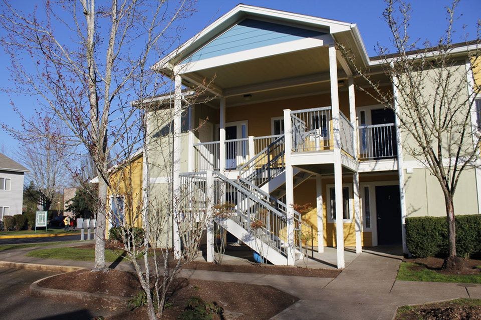 Exterior of a two-story apartment building with outdoor stairs and balconies
