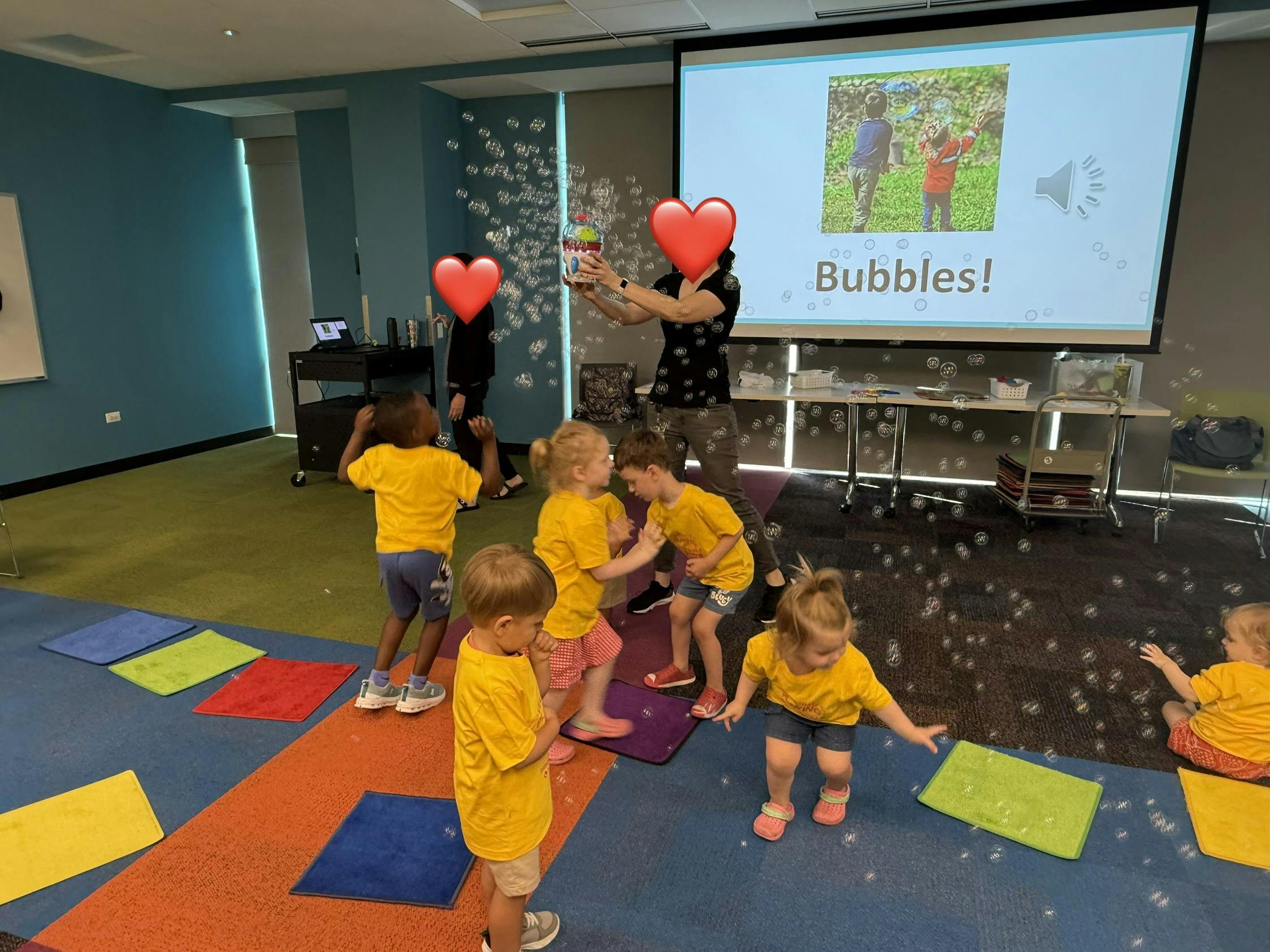 A teacher making bubbles for children wearing matching yellow shirts
