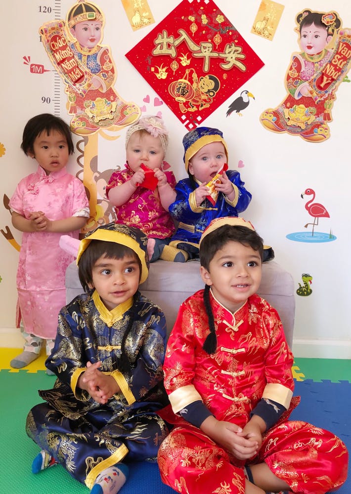 Five children in traditional clothing, some sitting, some standing