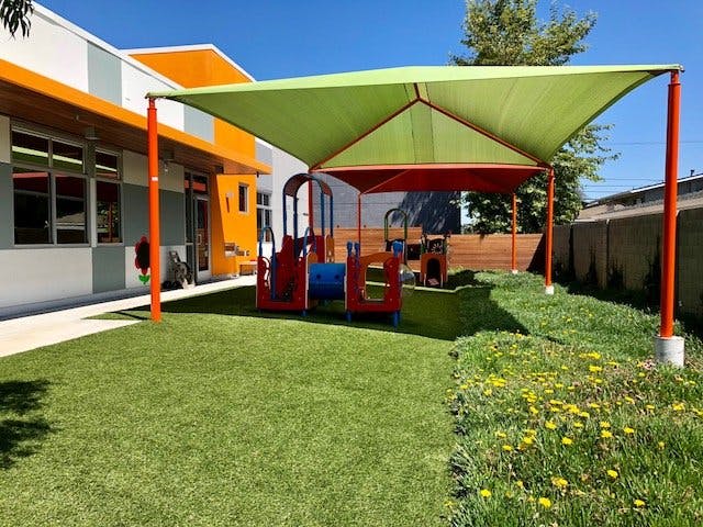 Outdoor playground with green turf and a shade structure