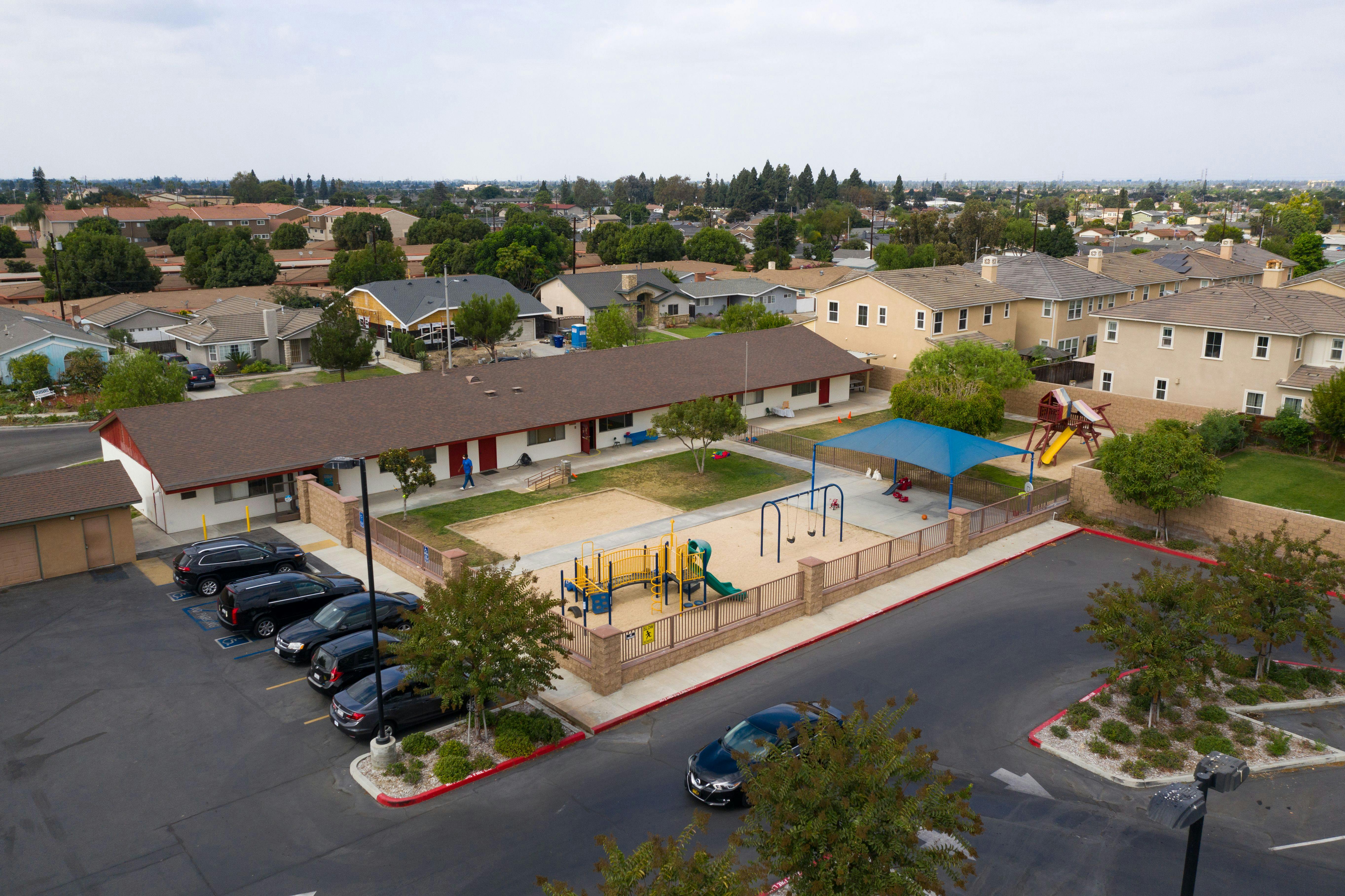 Aerial view of a building with a playground and parking lot