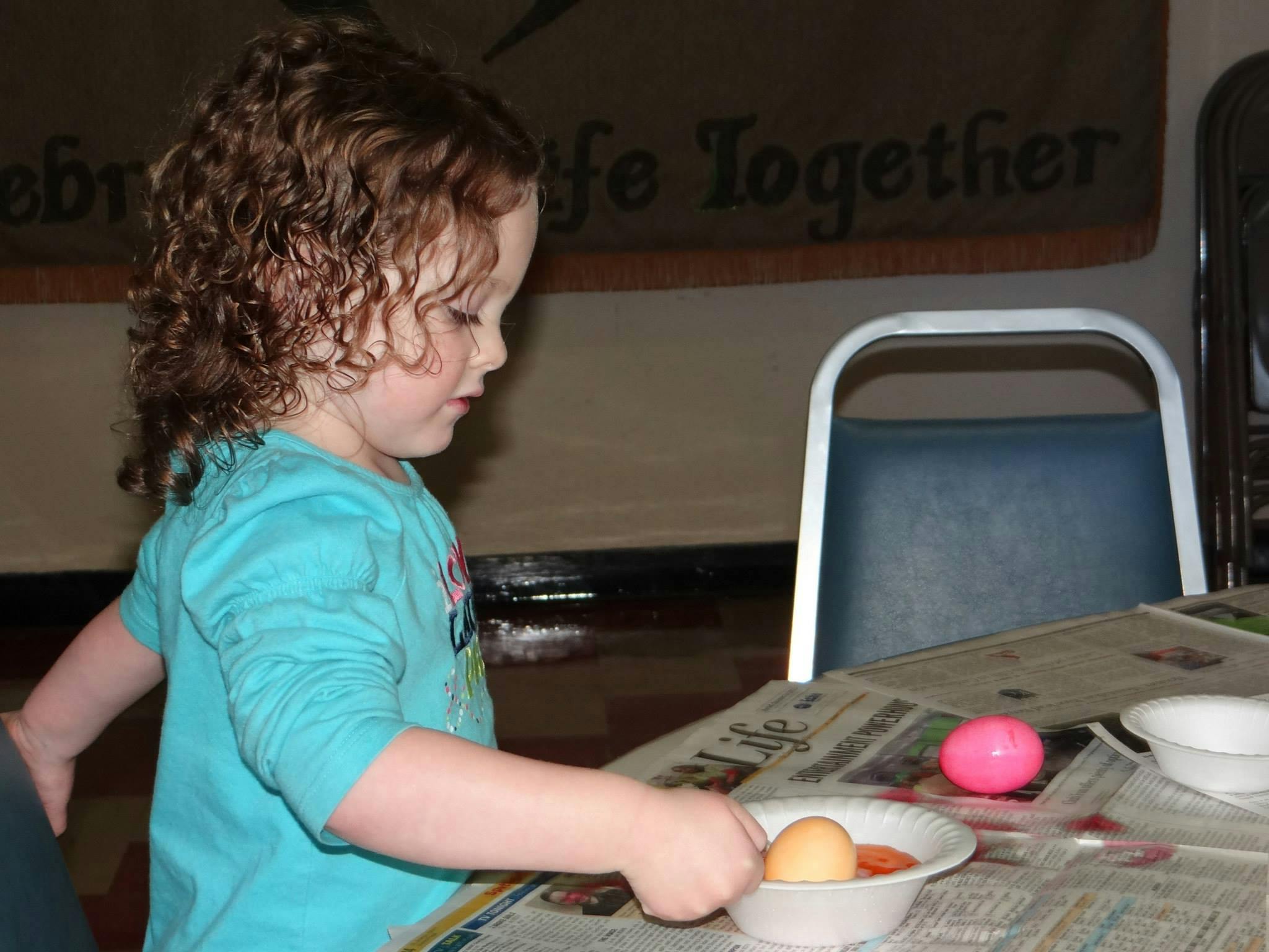 Child decorating an egg in a bowl