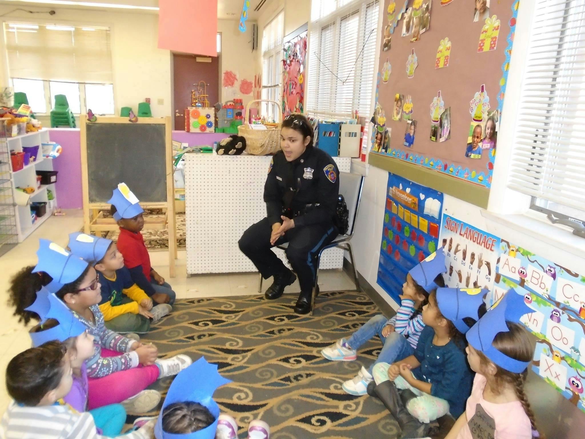 Police officer sitting on a chair talking to children sitting on the floor