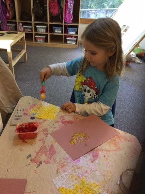 Child painting with a brush on paper at a table