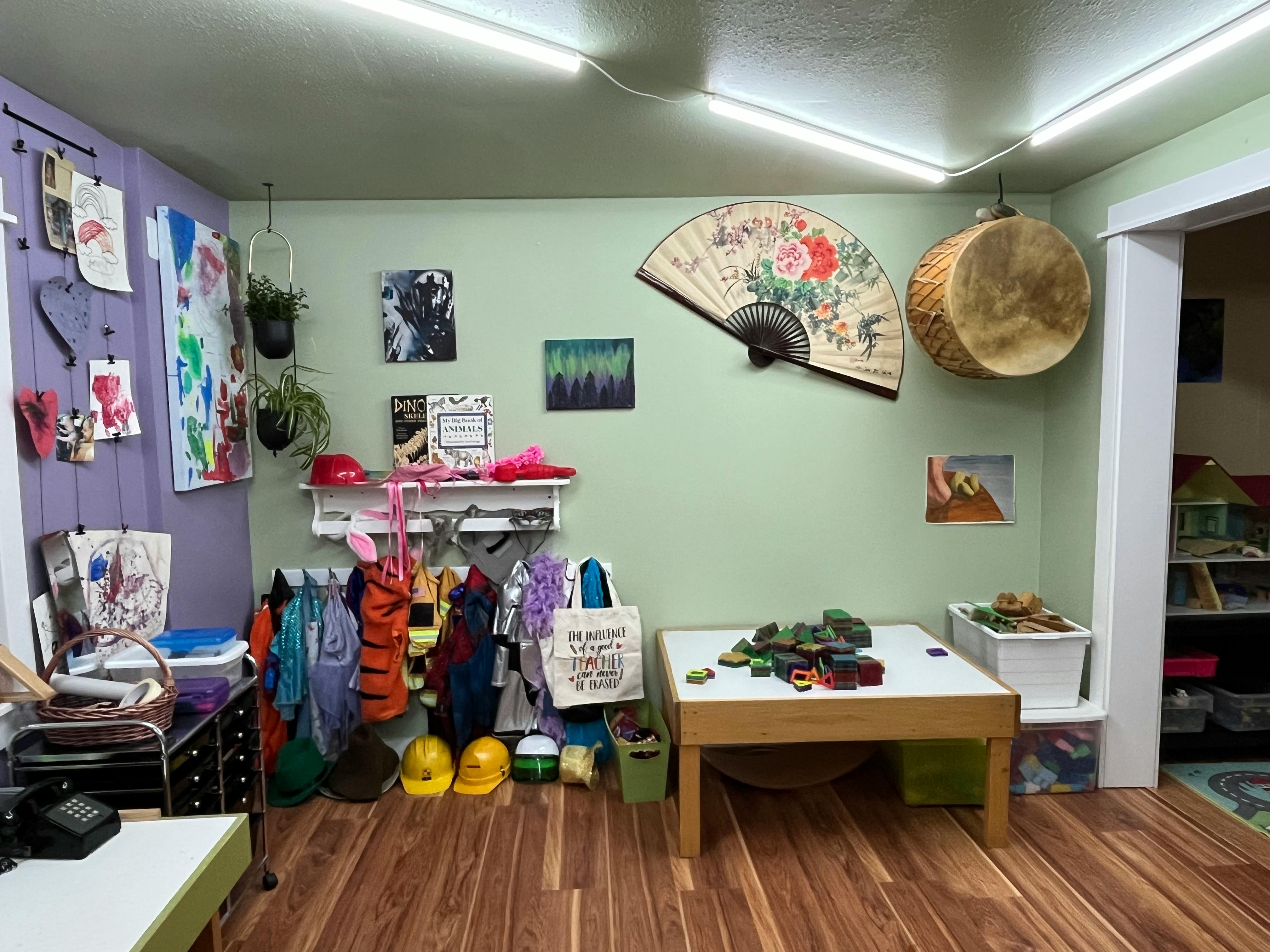 Classroom with clothes hanging on hooks, a table with items, and wall decorations